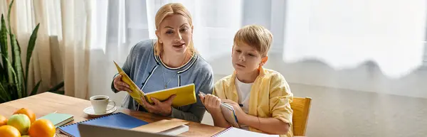 A mother and son enjoy reading together at a sunlit table. — Stock Photo