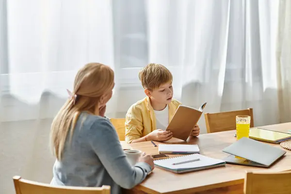 A mother enjoys a quiet moment with her son, who is deeply focused on a book. — Stock Photo
