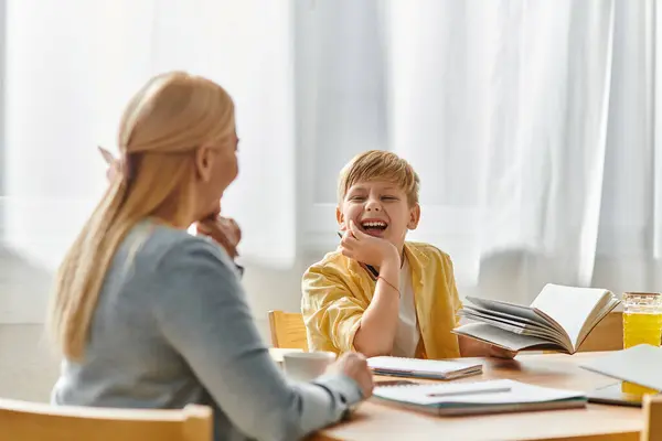 Mother and son share smiles while enjoying a cozy learning session at their kitchen table. — Stock Photo