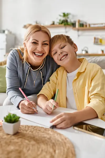 A woman and her son share laughter while drawing together at home, showcasing their strong bond. — Stock Photo