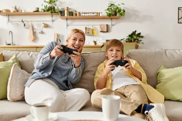 A woman and her son share laughter and excitement while playing video games together at home. — Stock Photo