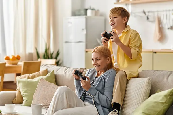 A woman and her son enjoy a fun gaming session on a soft couch, surrounded by comfort and warmth. — Stock Photo