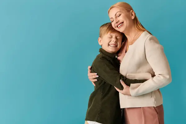 Une mère et son fils partagent une étreinte aimante, mettant en valeur la chaleur et la joie sur un fond lumineux. — Photo de stock