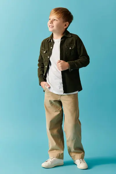 A smiling boy stands confidently against a bright blue backdrop, exuding warmth and joy. — Stock Photo