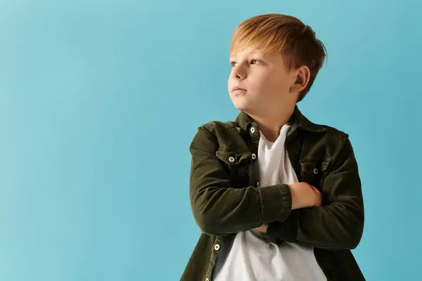 A confident young boy stands arms crossed against a bright blue playful backdrop. — Stock Photo