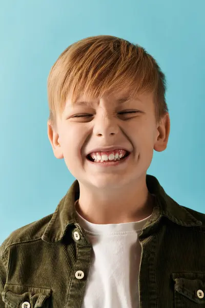 A cheerful boy expressing pure happiness as he posing on blue backdrop. — Stock Photo