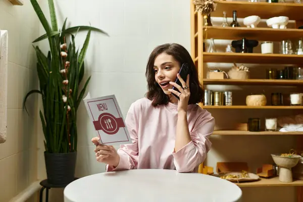 Young woman enjoys a delightful moment on the phone, exploring the menu in a chic cafe. — Stock Photo