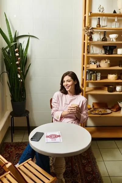Eine hübsche junge Frau lächelt, während sie an ihrem Drink in einem modernen Café nippt, umgeben von Dekoration. — Stockfoto