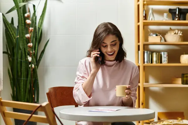 A young woman enjoys a warm drink while chatting on the phone in a stylish cafe. — Stock Photo