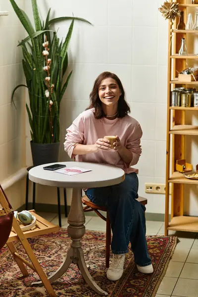 In a bright cafe setting, a young woman smiles warmly while holding a cup of coffee. — Stock Photo