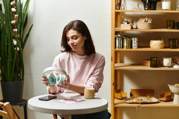 Relaxing in a vibrant cafe, a young woman sips her drink while exploring music options. — Stock Photo