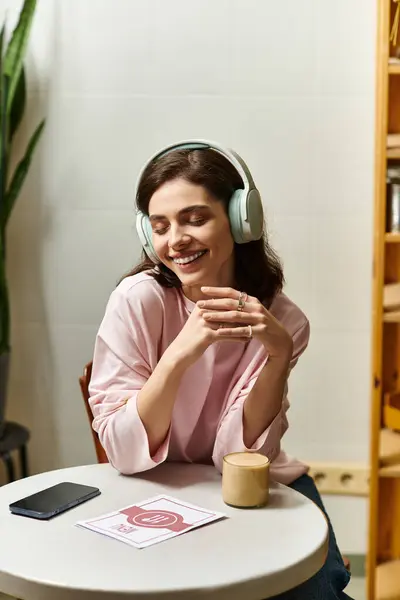 Uma jovem bonita relaxa em um café elegante enquanto usa fones de ouvido, sorrindo suavemente. — Fotografia de Stock