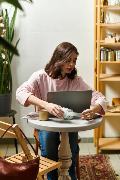 A young woman focuses on her laptop while enjoying a coffee in a stylish cafe workspace. — Stock Photo