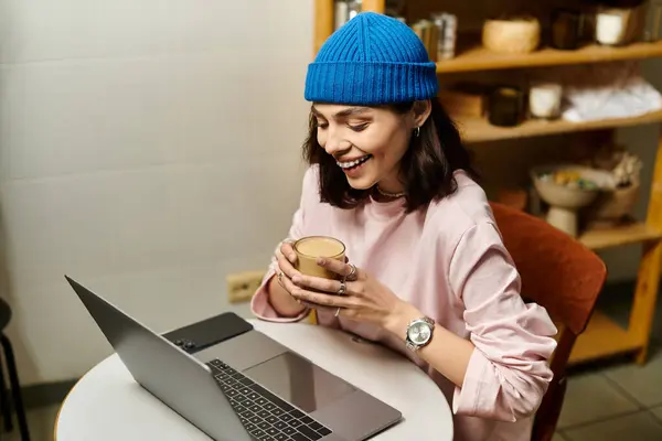 Bright atmosphere surrounds a young woman working on her laptop, sipping coffee. — Stock Photo
