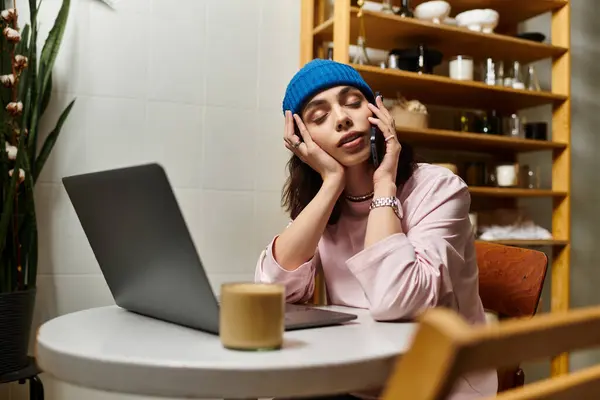 A beautiful young woman focuses on her work while multitasking on a call in a modern cafe. — Stock Photo