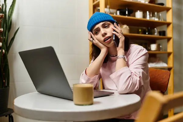 A young woman engages in remote work at a modern cafe, balancing her laptop and phone smoothly. — Stock Photo