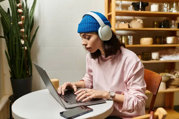 Freelancer typing on a laptop in a stylish cafe, focused on her work and enjoying the ambiance. — Stock Photo