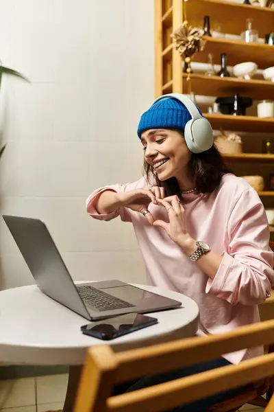 A young woman smiles while engaging in remote work at a modern cafe, wearing headphones. — Stock Photo