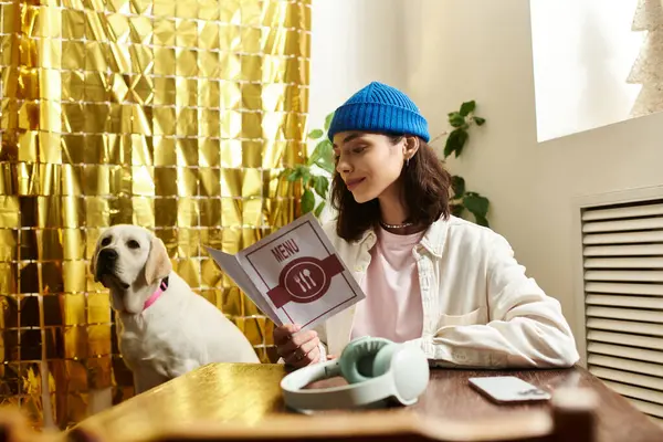 A young woman reads a menu while her labrador rests nearby in a modern cafe setting. — Stock Photo