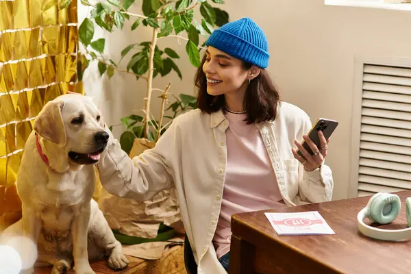 A young woman smiles as she interacts with her labrador in a modern cafe setting. — Stock Photo