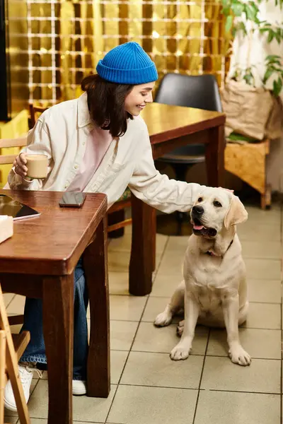 A young woman with her labrador enjoys quality time at a modern cafe filled with warmth. — Stock Photo