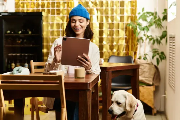 A cheerful young woman interacts with her labrador in a stylish pet-friendly cafe. — Stock Photo