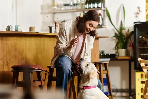 Una joven disfruta del tiempo de calidad con su labrador en un acogedor café que acepta mascotas. - foto de stock