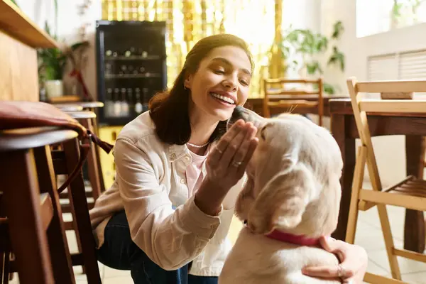 In a modern pet friendly cafe, a young woman enjoys quality time with her labrador. — Stock Photo