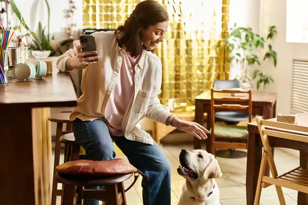 A cheerful young woman shares a moment with her labrador in a vibrant cafe setting. — Stock Photo