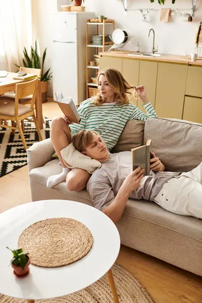 Una joven pareja comparte un momento acogedor en casa, comprometida con sus libros, llena de afecto. - foto de stock