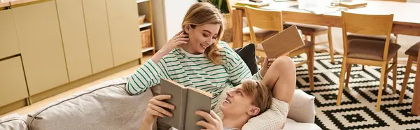 Loving couple relaxes on the couch while sharing a book, creating a warm and inviting atmosphere. — Stock Photo