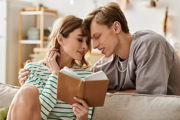 Loving couple shares a cozy moment while reading together on a comfortable couch at home. — Stock Photo