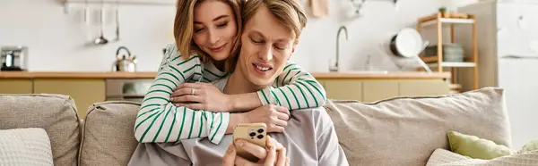 A cheerful young couple happily cuddles on their cozy couch while sharing a joyful moment together. — Stock Photo