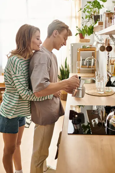 A young couple enjoys each others company while preparing coffee in their warm, inviting kitchen. — Stock Photo