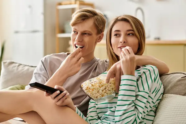 In a stylish living room, a couple sits closely on the couch, sharing laughter and popcorn. — Stock Photo