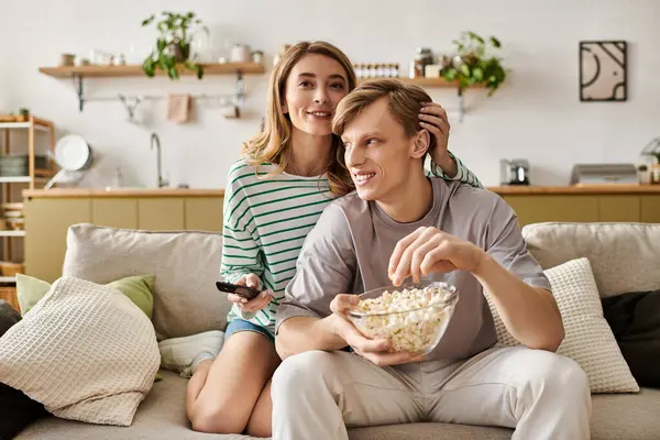 Young couple relaxes on a comfortable sofa, sharing popcorn and creating joyful memories. — Stock Photo