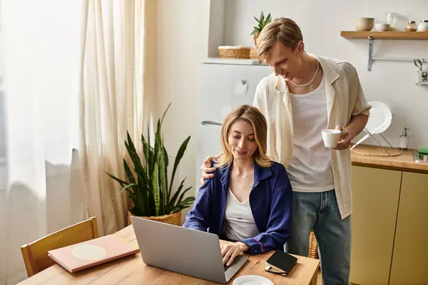 A couple enjoys a cozy moment, with her on her laptop and him bringing coffee and attention. — Stock Photo