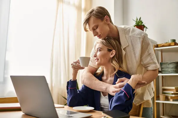 Una coppia amorevole condivide un momento intimo a casa mentre si gode il caffè e lavora su un computer portatile. — Foto stock