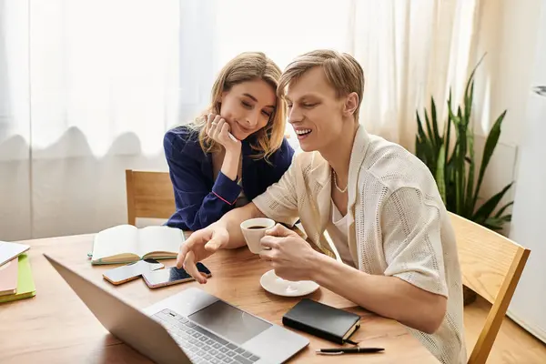 Young couple enjoys a cozy moment at home, sharing smiles and hot coffee while working together. — Stock Photo
