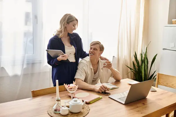 A joyful young couple shares a warm embrace while engaging in a creative activity at home. — Stock Photo