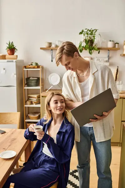 Loving couple shares a warm moment while sipping coffee and working on a laptop at home. — Stock Photo