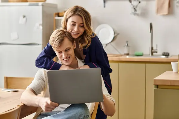 Loving partners sit close in their stylish kitchen, immersed in laughter and shared screen moments. — Stock Photo