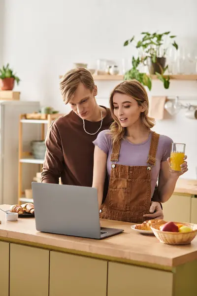 A loving couple shares a warm moment in their cozy kitchen while exploring a laptop together. — Stock Photo
