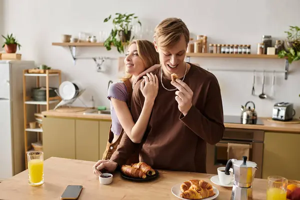 A young couple enjoys breakfast at home, sharing laughter and love in a cozy atmosphere. — Stock Photo