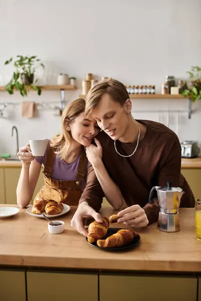 A loving couple enjoys a delightful breakfast of croissants and coffee in their inviting kitchen. — Stock Photo