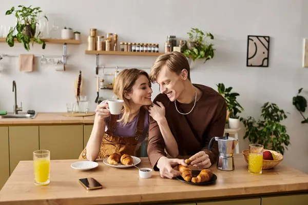 A young couple enjoys a delightful breakfast together at home, sharing smiles and croissants. — Stock Photo
