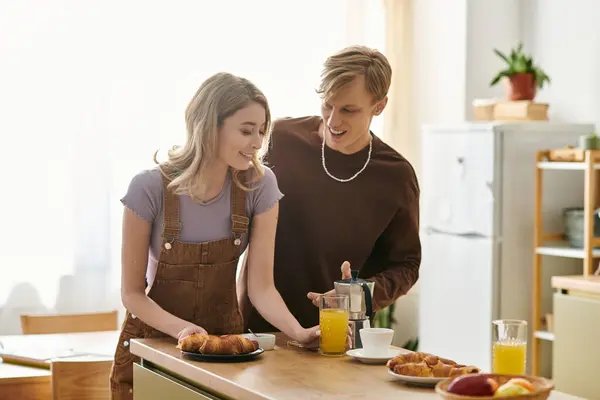 Una pareja cariñosa disfruta de una mañana alegre en casa, haciendo el desayuno y apreciándose mutuamente. - foto de stock