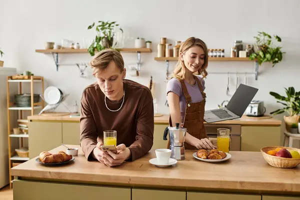 Una giovane coppia si gode la colazione a casa, condividendo bevande e dolci mentre sta insieme. — Foto stock