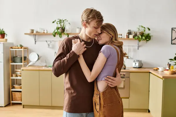 A young couple embraces warmly in their trendy, green filled kitchen. — Stock Photo