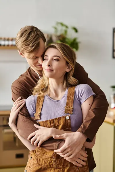Pareja joven se abraza en su casa bellamente decorada, irradiando calidez y afecto. - foto de stock